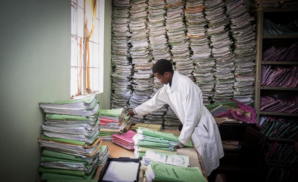 Stacks of paper medical records and administrative paperwork